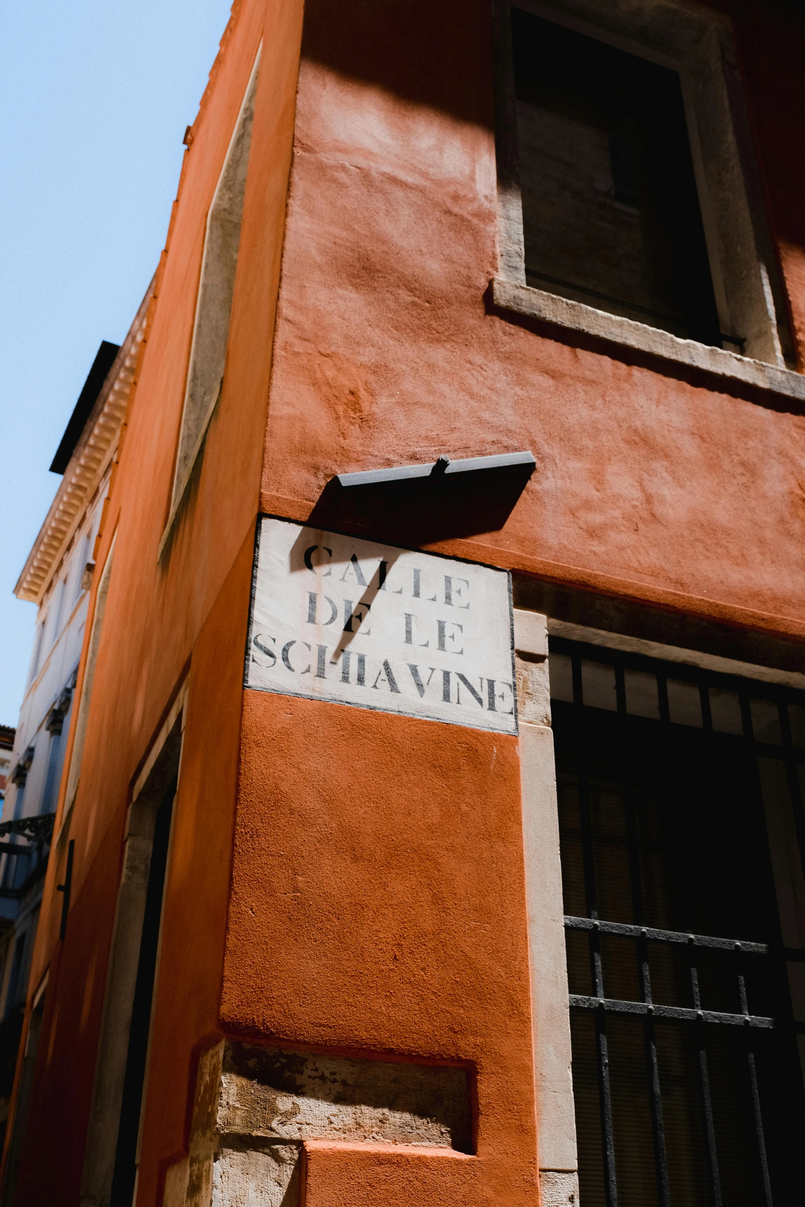 the old iron grilled door is near an orange building