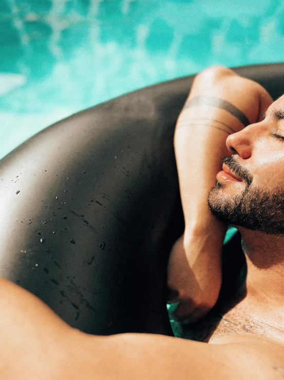 a man is laying in a pool with his arms hanging out