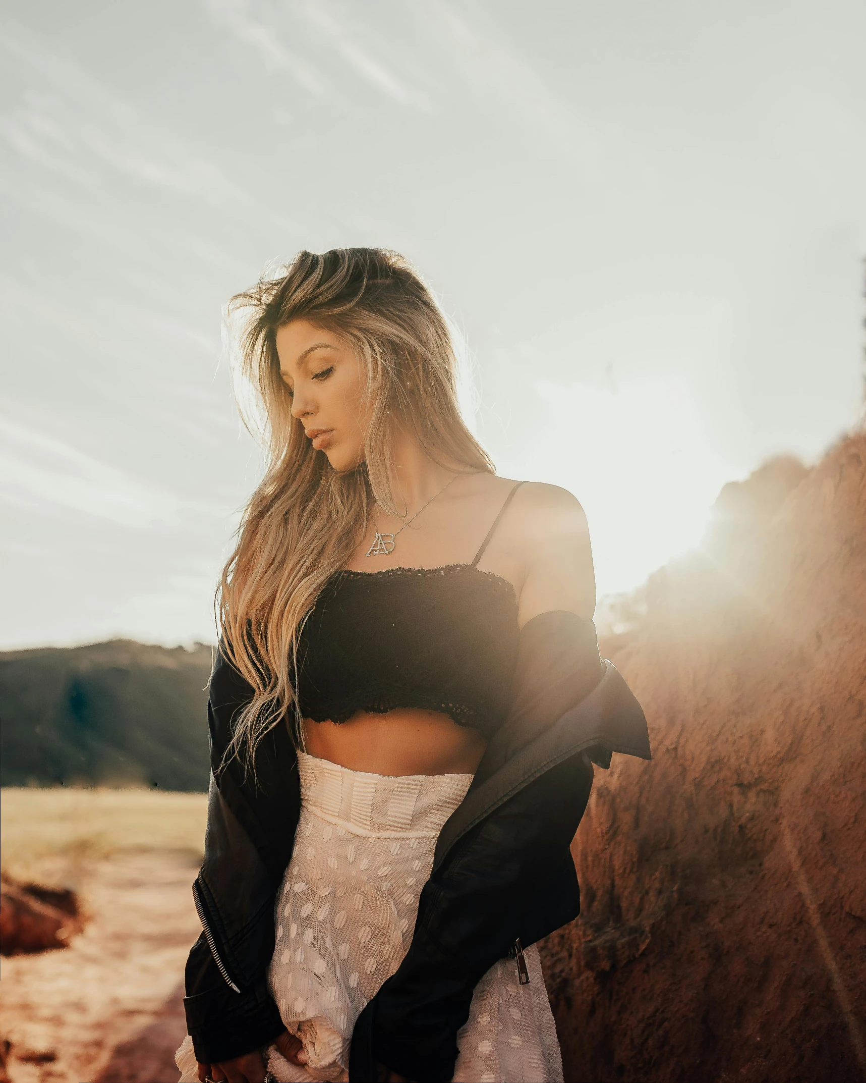 woman with long hair standing next to rocks in a field