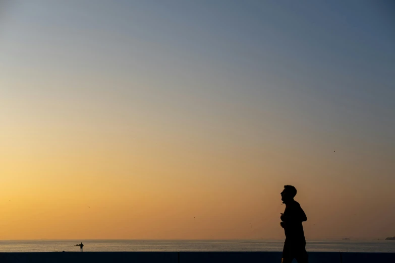 a person standing by the ocean watching the sunset