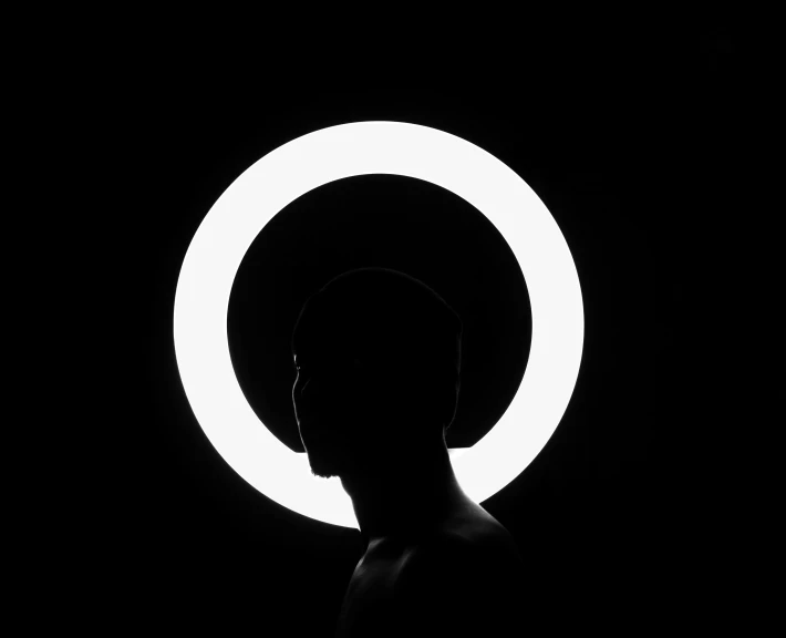 a man in the darkness looking at a circular object