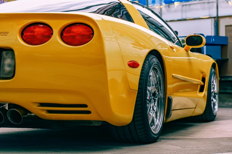 a yellow sport car is parked next to a building