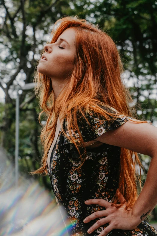 a woman standing in the sunlight, with her hair blowing back and looking upwards