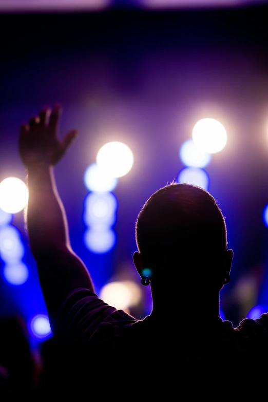 a man in silhouette at a concert with his arms raised