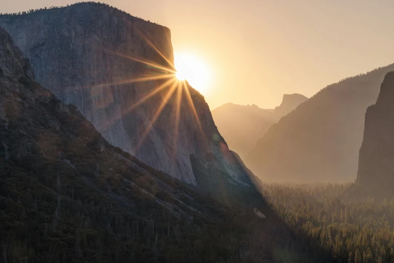 the sun setting over a cliff and mountain side