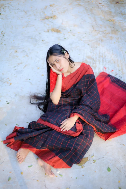 a girl sitting in the sand with her hand on her face