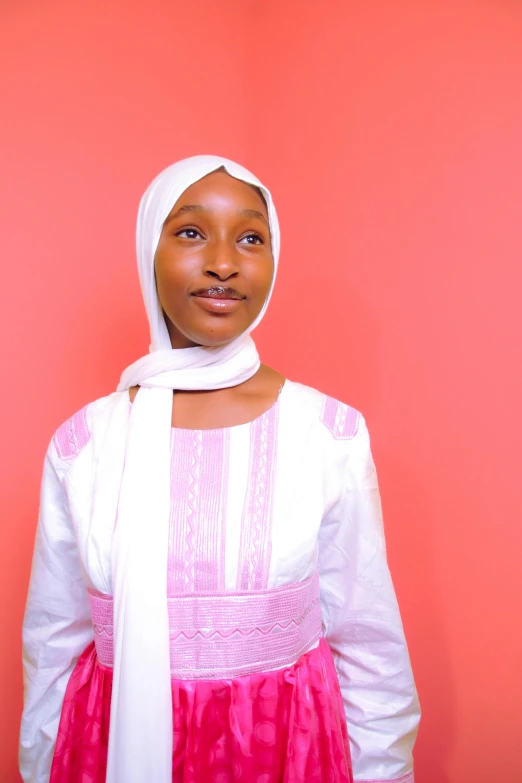 a woman is standing against a pink background