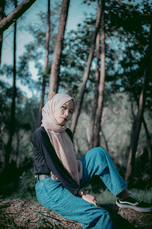 a woman in hijab sitting on a tree stump