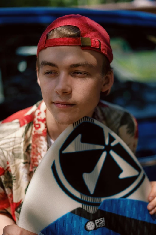 a young man with red hair and a hat holding a surfboard