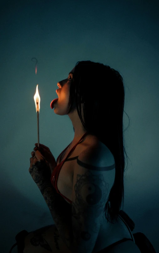 a woman holding up a lit candle in the dark
