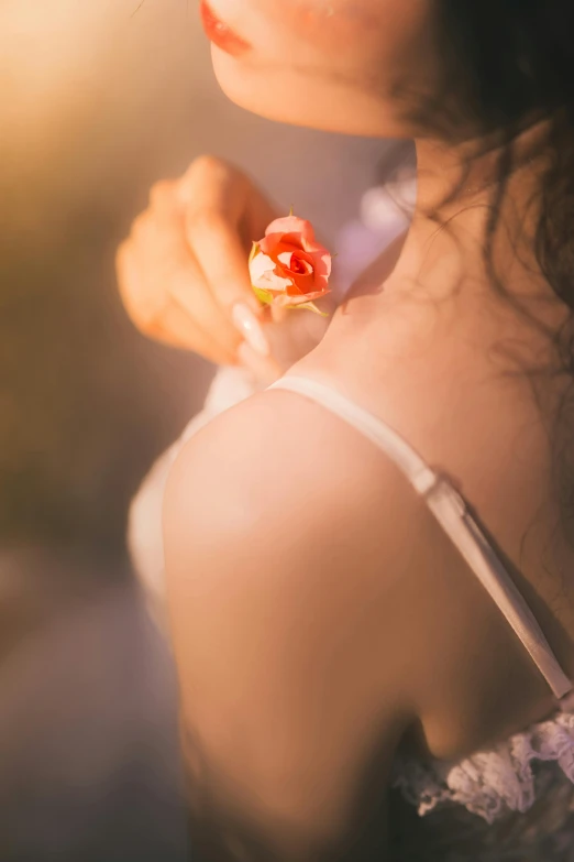 a woman's shoulder is holding soing up and a flower that is in her right hand