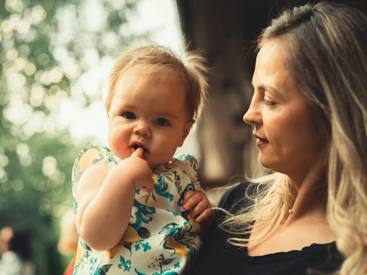 a lady holding her baby who is in a dress