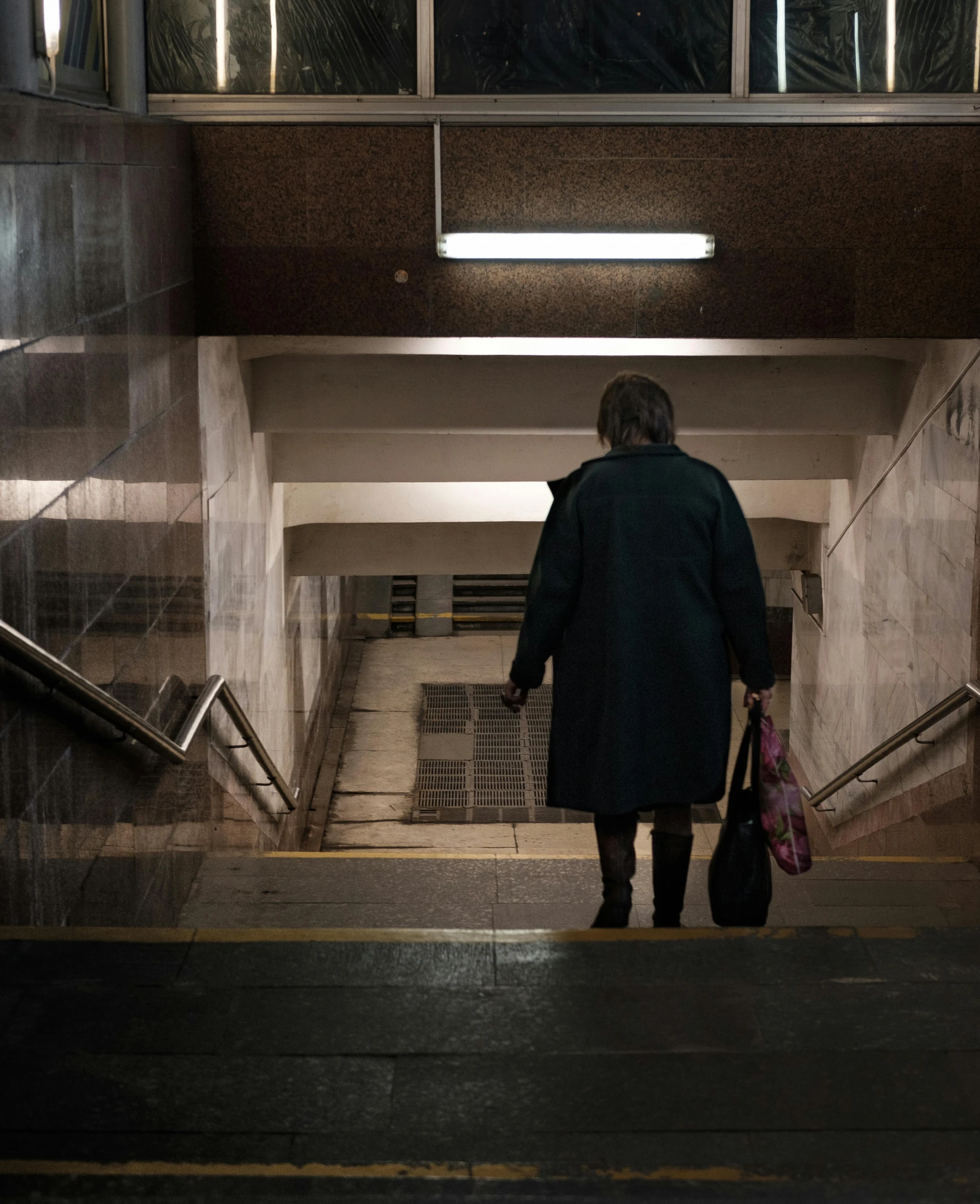 an old lady walking through a tunnel with a handbag