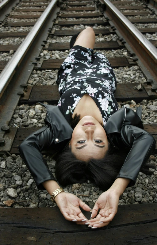 a woman laying on the ground near train tracks
