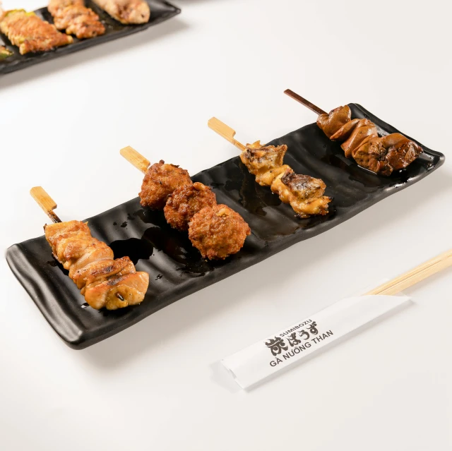 some chicken skewers are sitting on a black plate