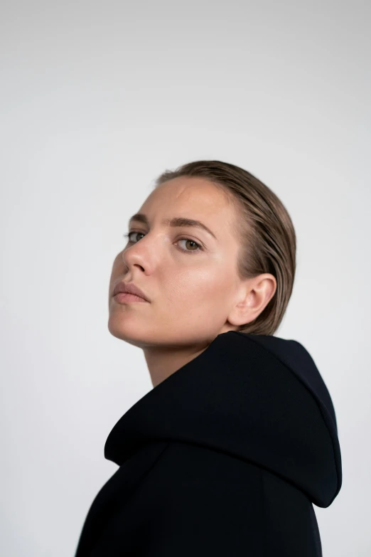 a woman in a black coat looks off into the distance