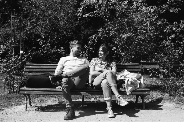 black and white pograph of people sitting on park bench