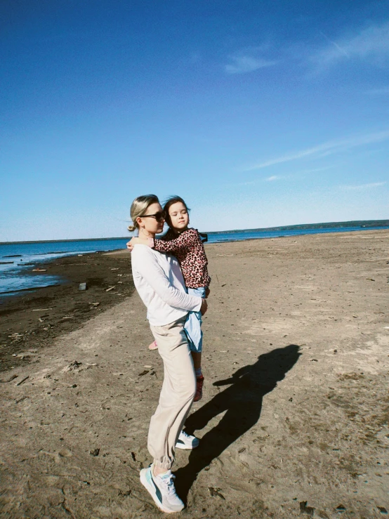 a man holding a little girl while walking on a beach