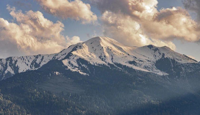 some snow mountain peaks and some clouds on a blue sky