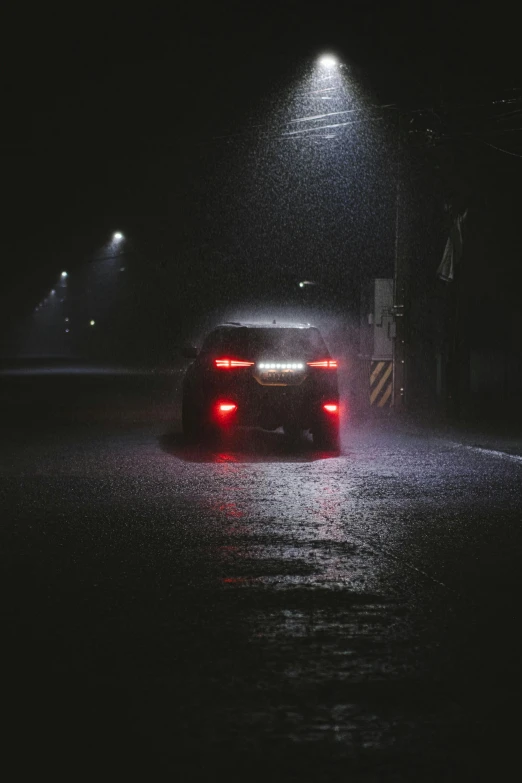 a car driving through a street light on a wet night