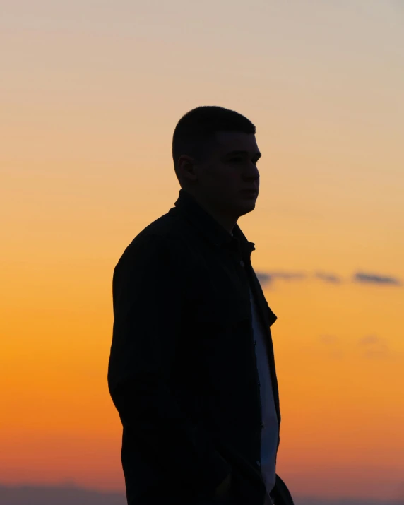 a man standing on the side of a hill at sunset