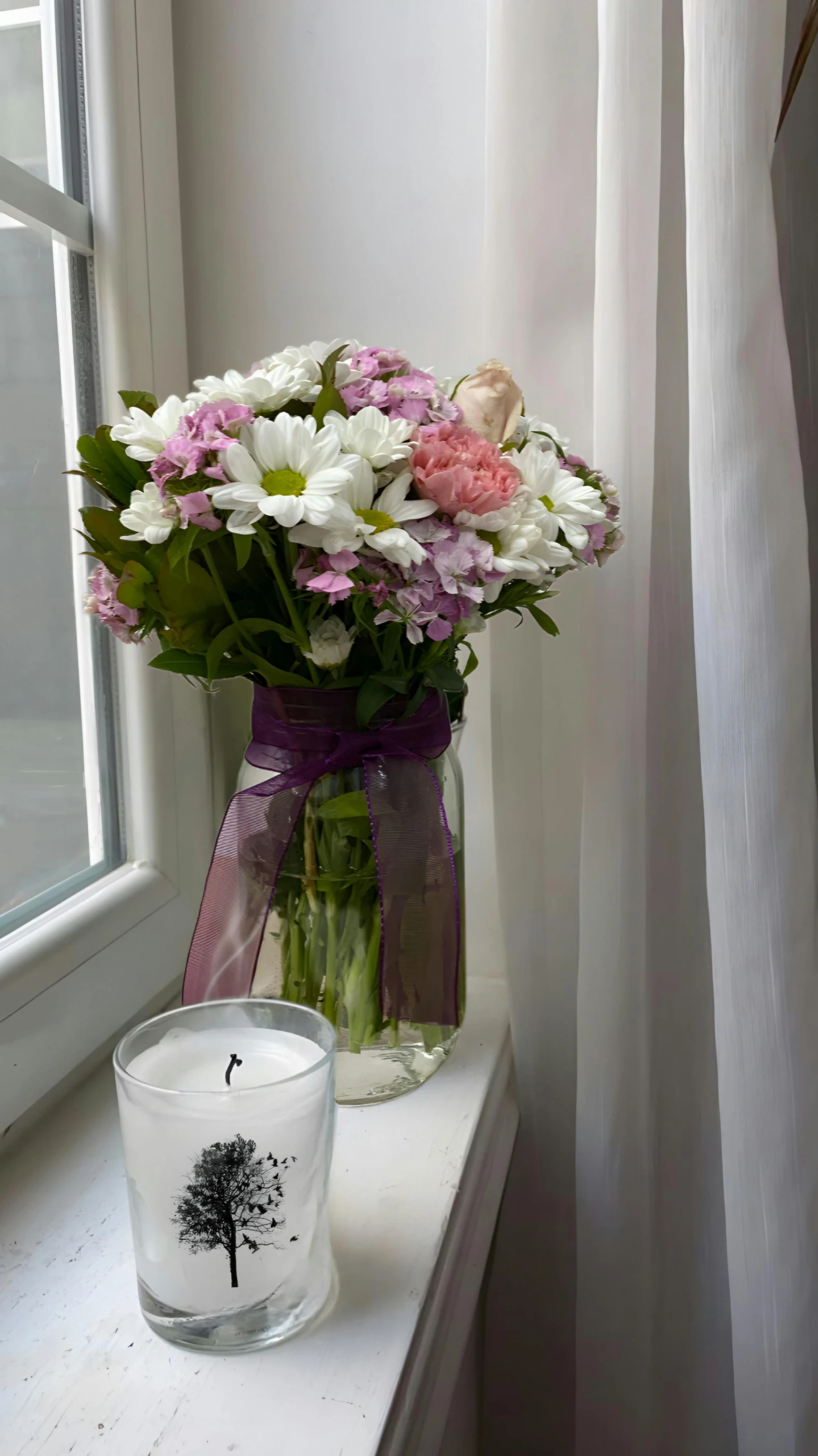 a glass vase with flowers next to a candle