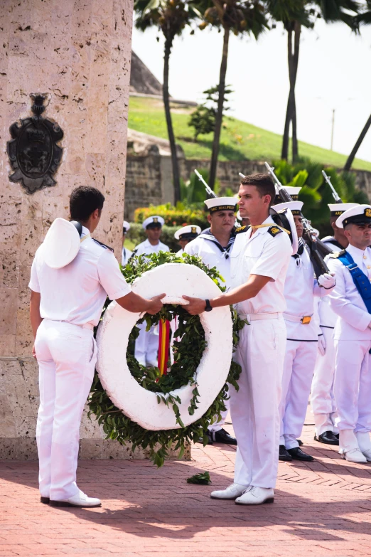 sailors and an official handing soing to a man in white