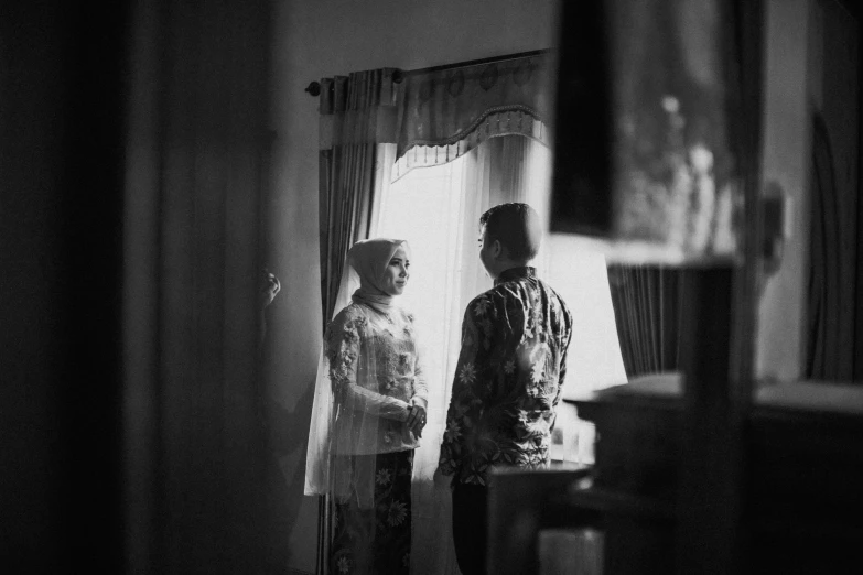 two men standing in front of a window in a house