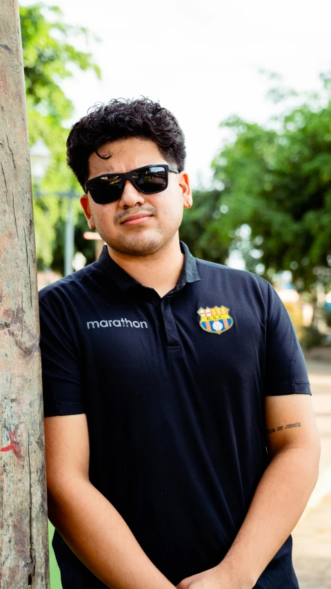 a man is leaning against a tree in sunglasses