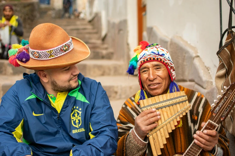 two men wearing colorful headgear, one playing the guitar