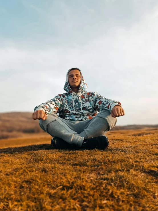 a man is sitting on the grass meditating