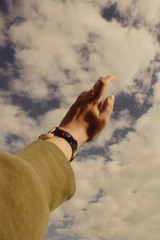 a man in a beige sweater is holding his hand high in the sky