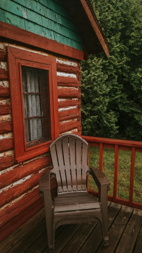 an empty chair on a wooden deck next to a log house