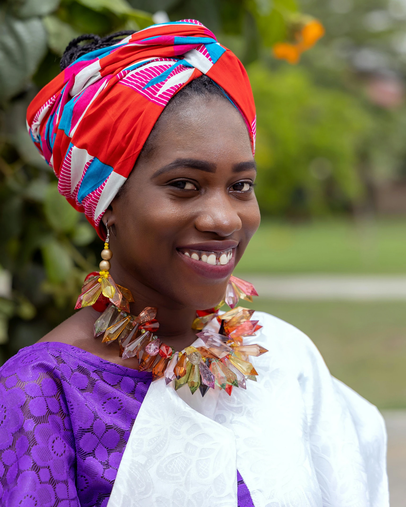 a young woman wearing brightly colored earrings stands outside