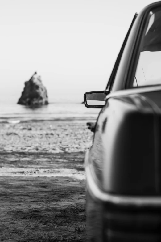 a black and white po of a car parked on the beach