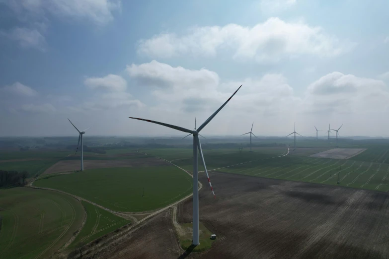 several wind turbines in an open field and trees