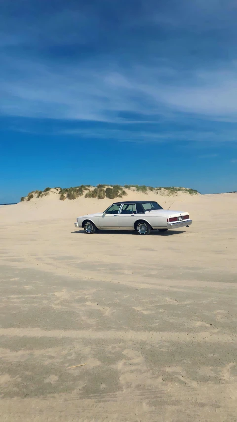 a white car sitting in a sandy area