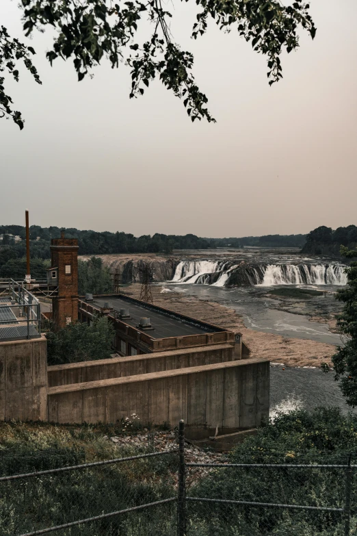 a view of a dam and the falls from behind a fence