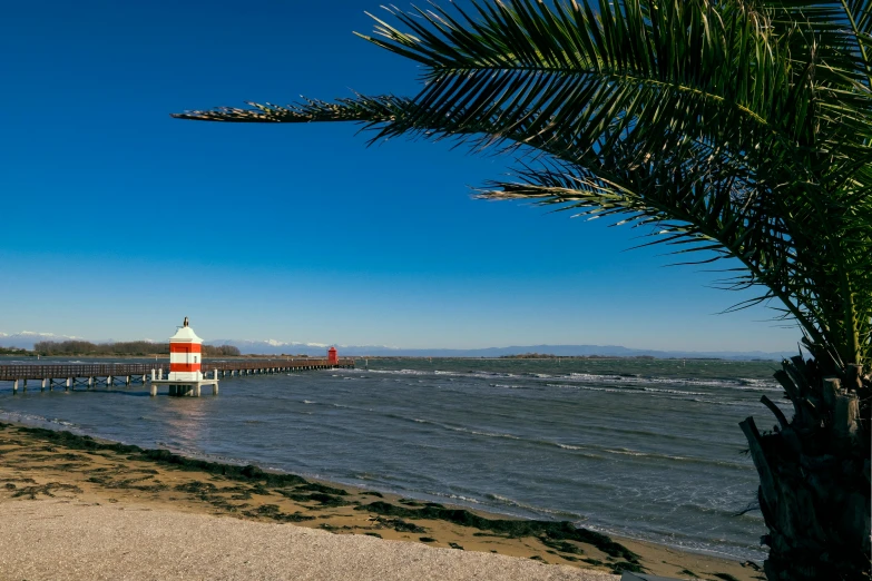 a white and red lighthouse on an ocean shore with waves in the water