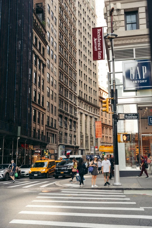 some people walking across the street near tall buildings