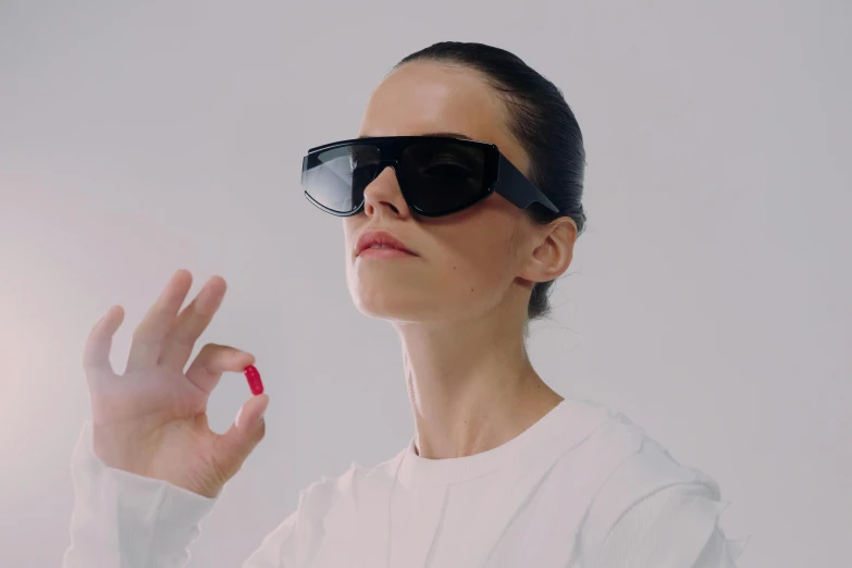 a woman in sunglasses is holding her finger up