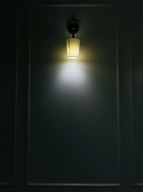 a dim, light - colored wall mounted lamp against black background