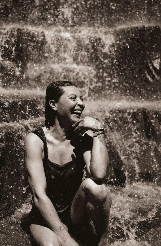 woman in wetsuit posing in front of a waterfall