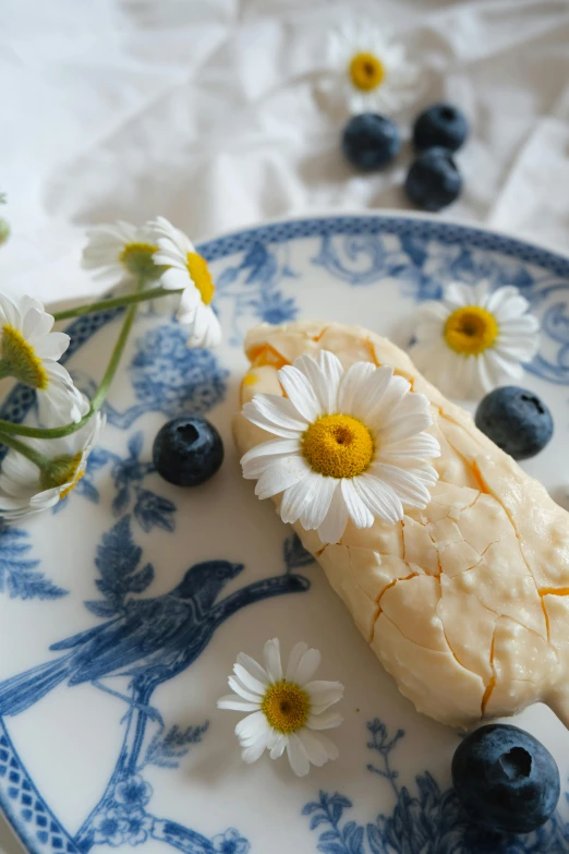 a piece of pie on a plate with flowers and blueberries