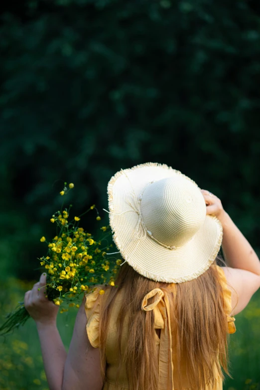 a girl with long red hair holding a yellow flower