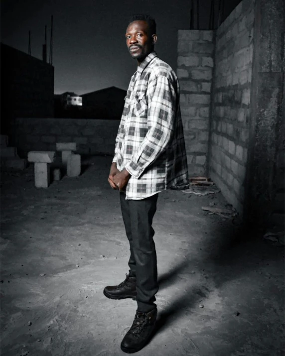 a man posing in a dark room wearing jeans