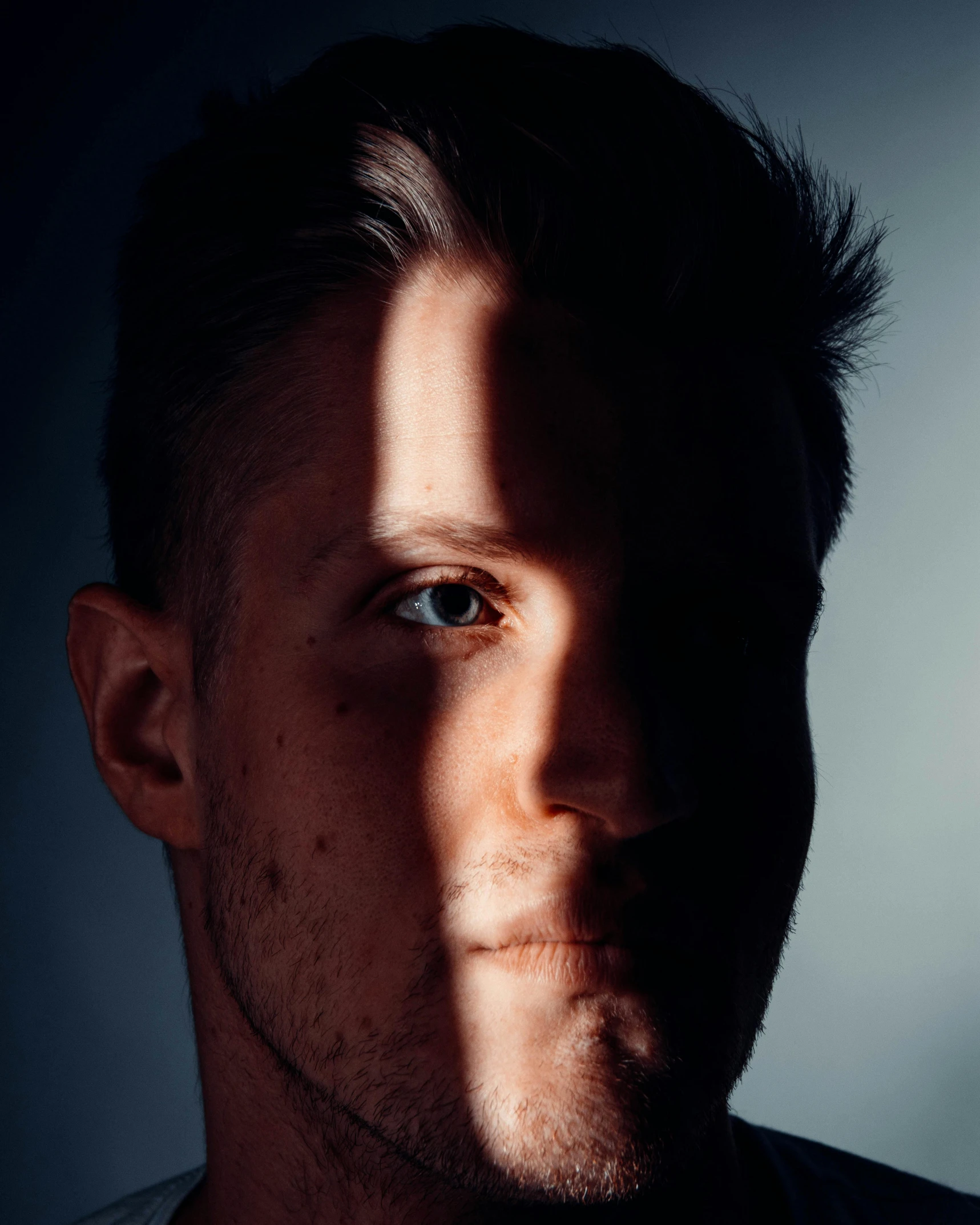 an attractive man with short hair and blue eyes looks away from the camera