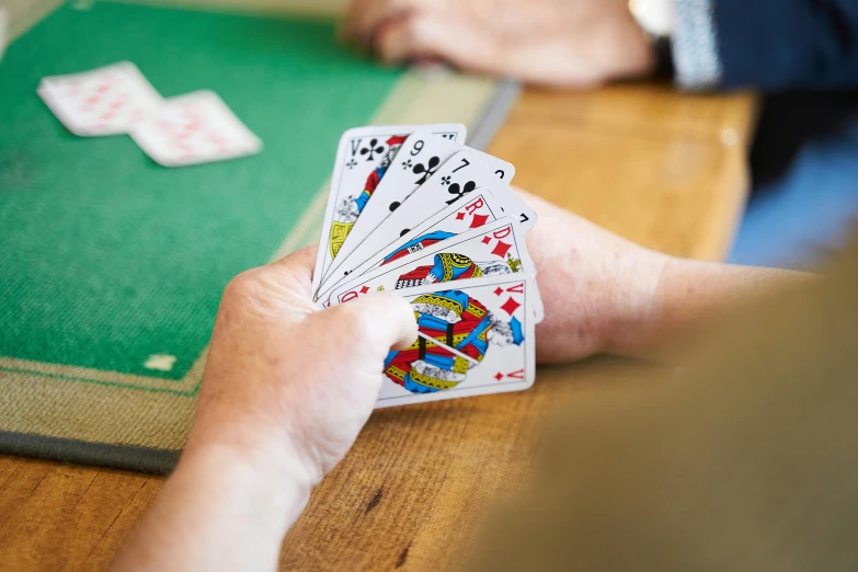 hands holding cards next to playing card board