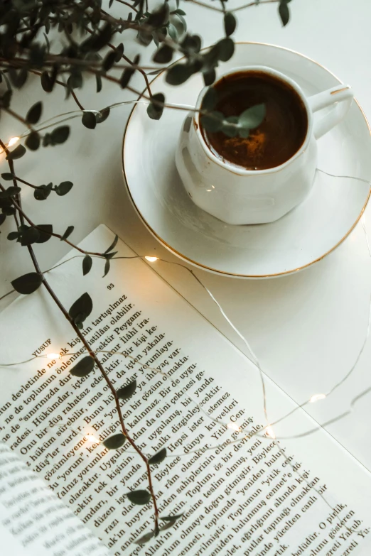 an open book sitting on top of a table next to a cup of coffee