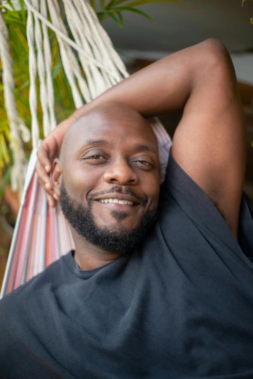 a man is sitting in a hammock with a smile